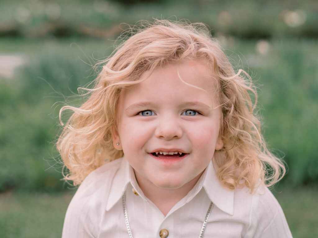 Blonde hair, blue eyed boy smiling at camera.