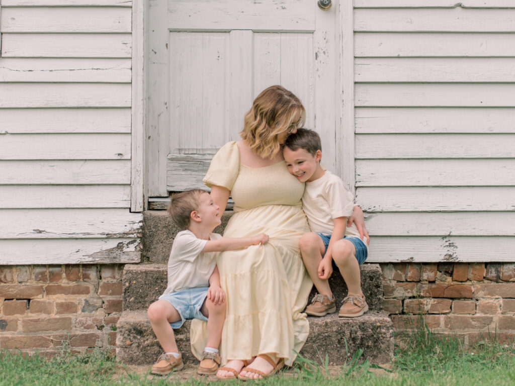 Mom snuggling her two boys on the steps of a historic home in Virginia