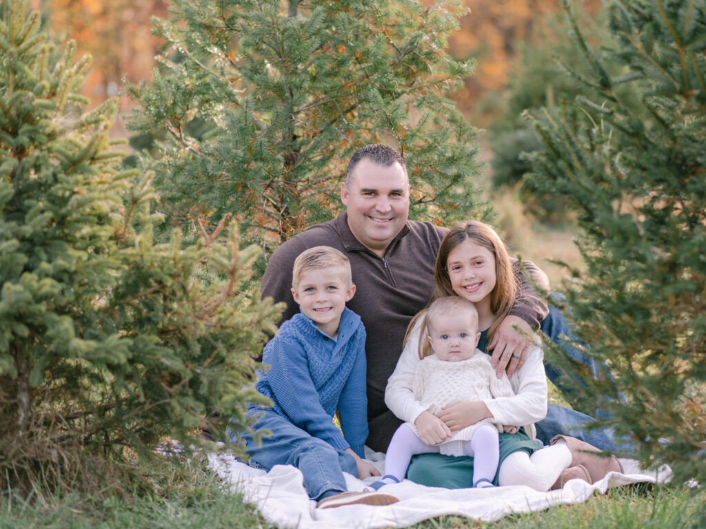 A Dad and his three young children smiling at Southern Maryland Tree Farm.