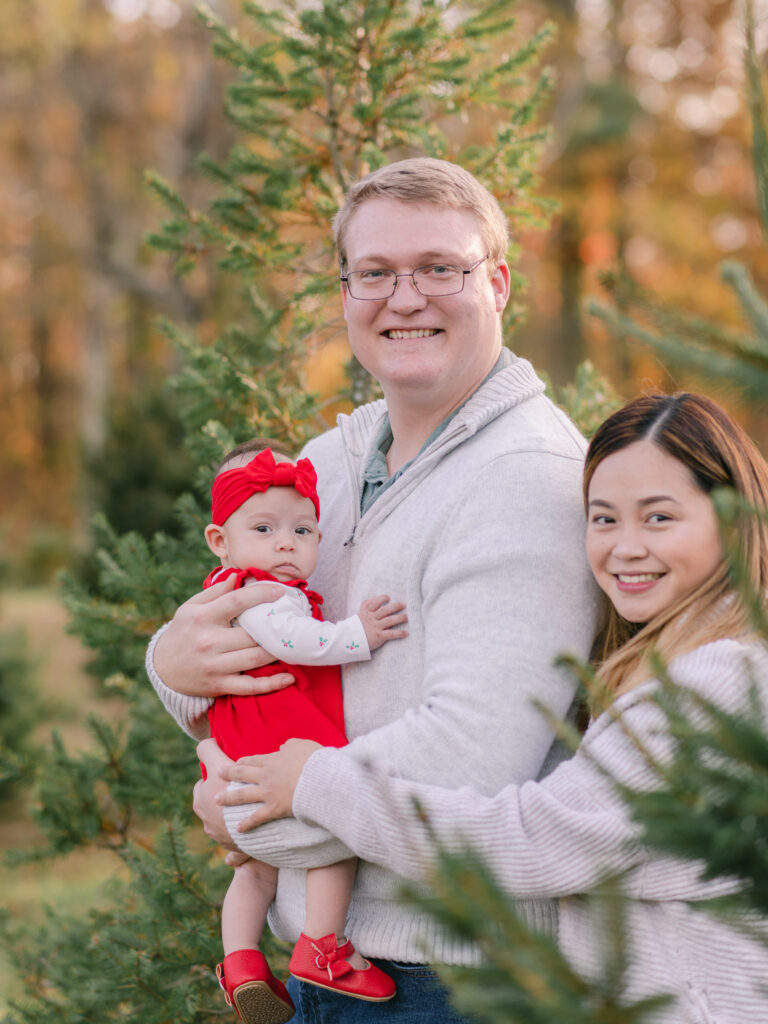 Dad holding his newborn daughter and hugging his wife during Tree Farm Photos.
