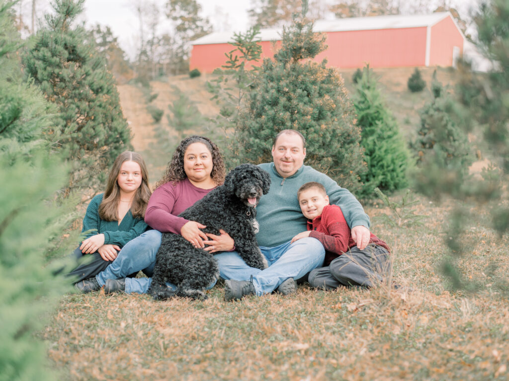 A Southern Maryland family with their black dog at Southern Maryland Christmas Tree Farm.
