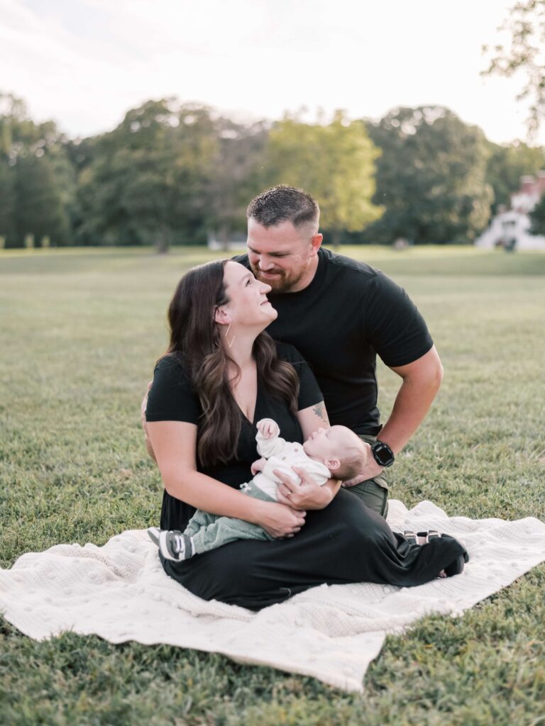 New parents in black outfits at Virginia park holding newborn son.