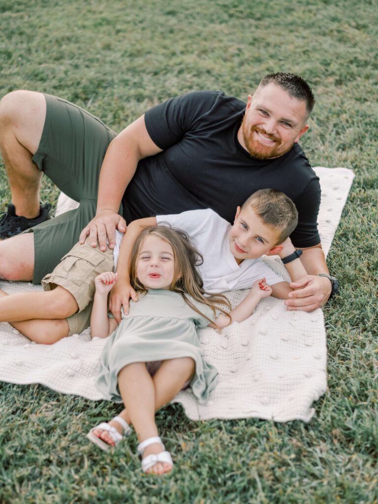 New Dad laying on blanket with son and daughter in vriginia.