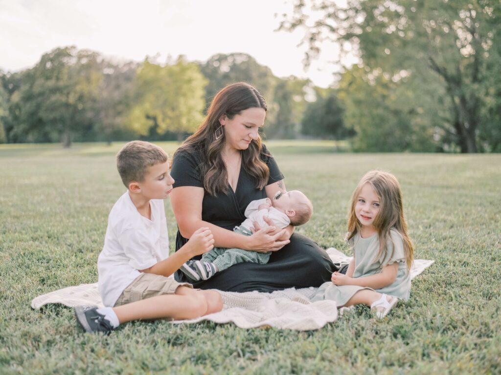 A mom in black dress holding her newborn with her two older children during Virginia family photo session.