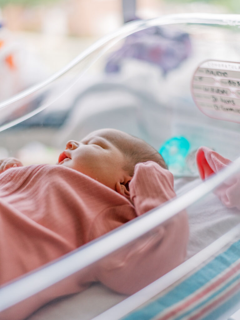 Newborn baby laying in bassinet at a local Southern Maryland hospital wearing a pink outfit
