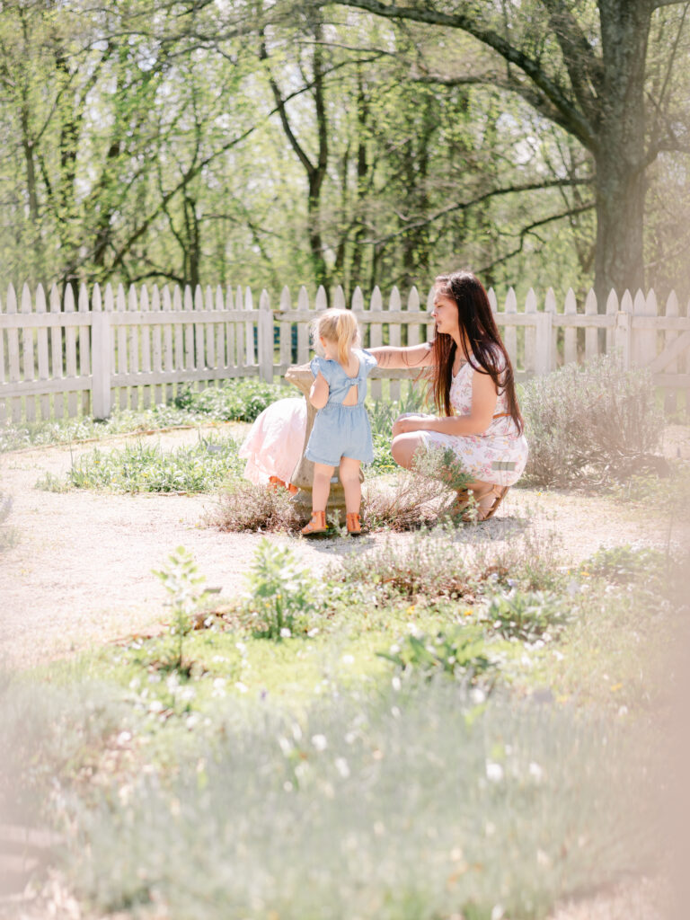 Young mom with long black hair and her two young daughters in garden area of Smallwood State Park. 