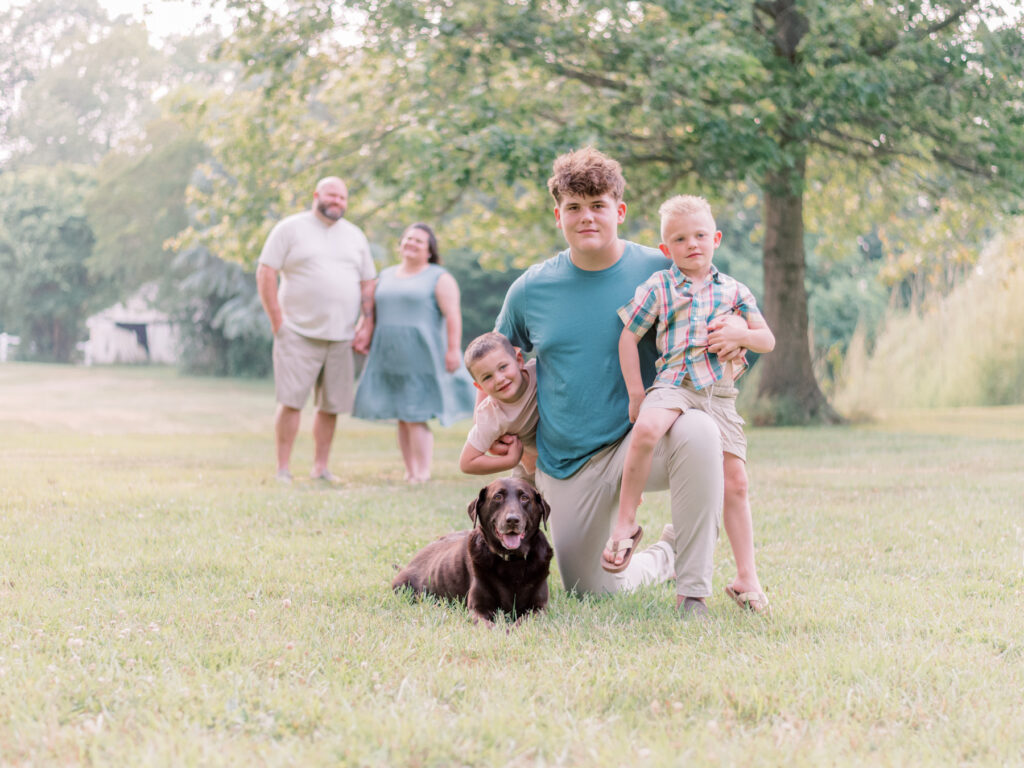 Mom and Dad looking at young sons and family dog during photo session in St. Marys County.