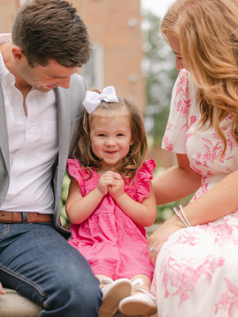 Little girl smiling while her parents look at her.