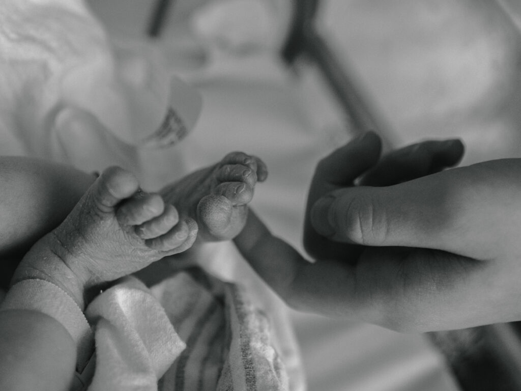 Older brother touching his newborn sisters feet.