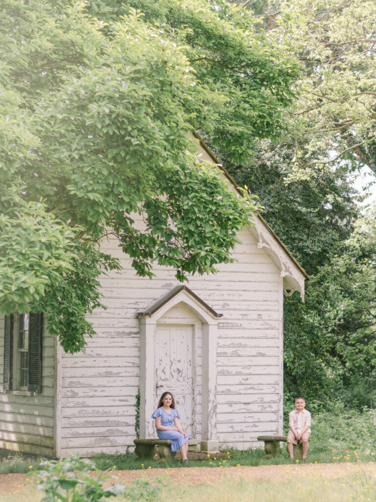 Twin brother and sister sitting in front of small white church at Greenwell State Park.