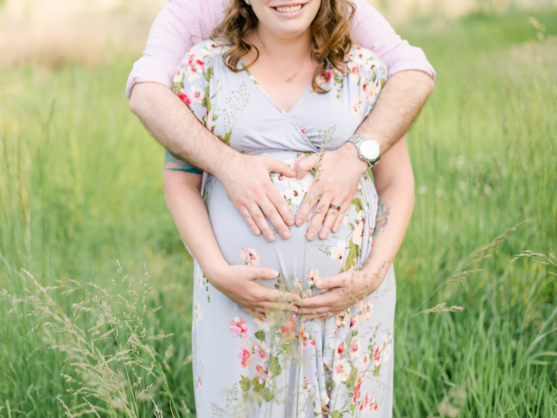 Dad and mom in field holding pregnant belly