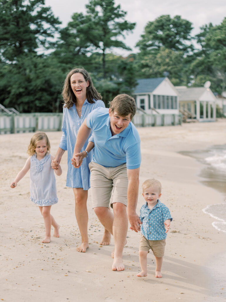 Family of four laughing and playing on beach in Virginia.